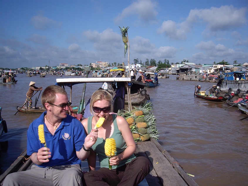 Tourists taste fresh fruit in Cai Be floating market