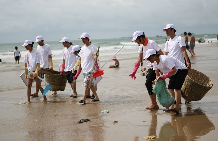 Tourists picking up trash on the beach of Cat Ba Island