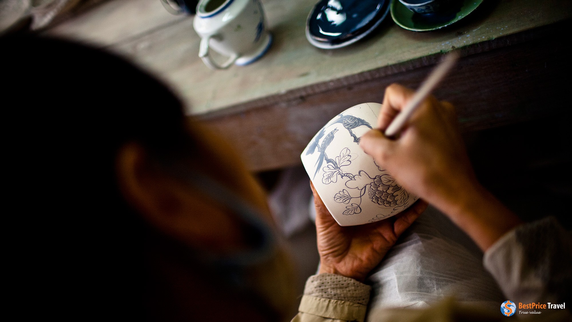 Artisan decorating a ceramic vase.