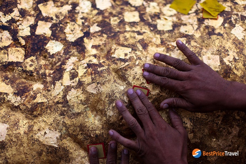 The rock's surface is covered with layer after layer of thin golden leaf