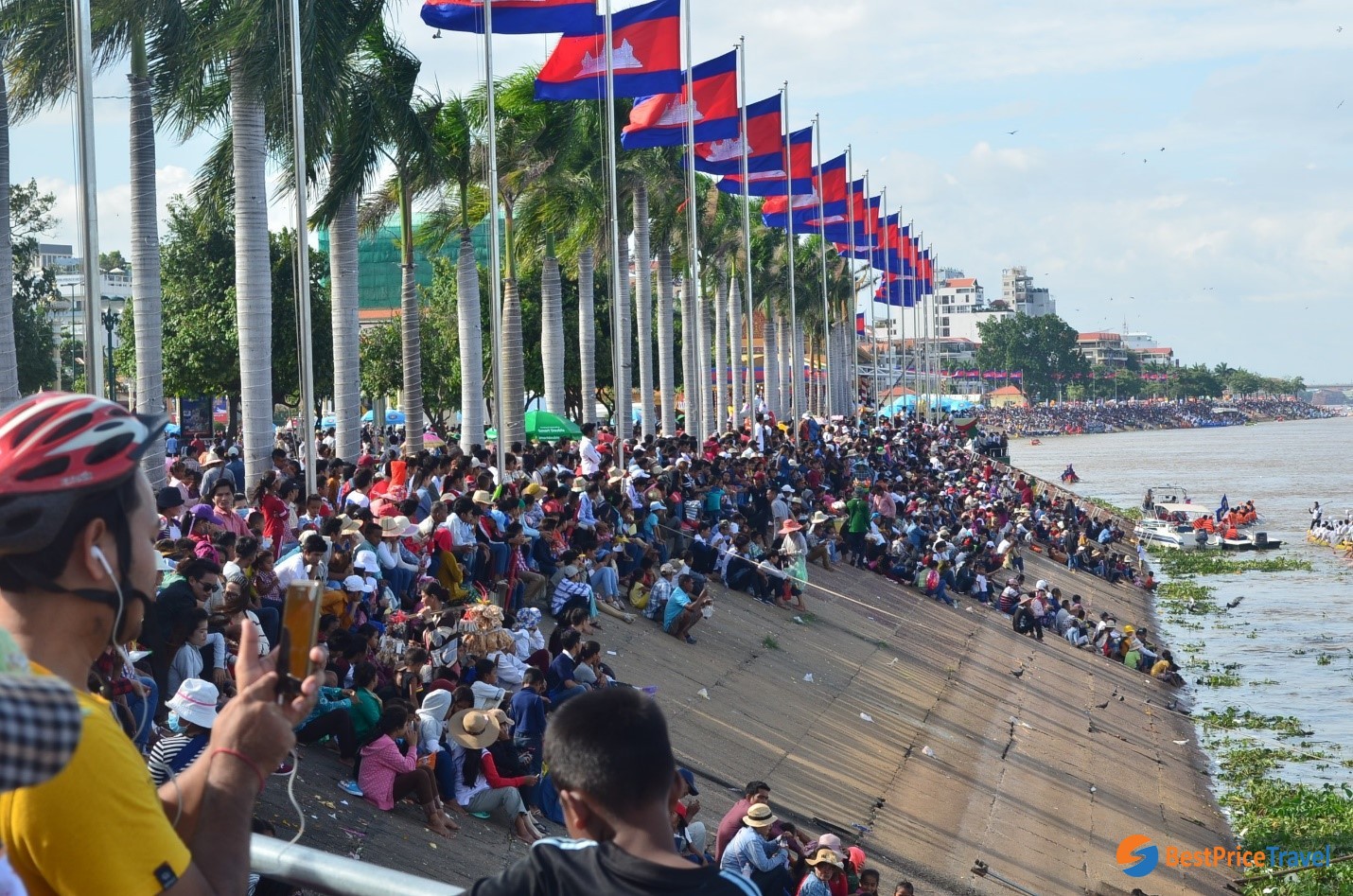 Spectators on the riverbank are cheering for their teams in rowing festival