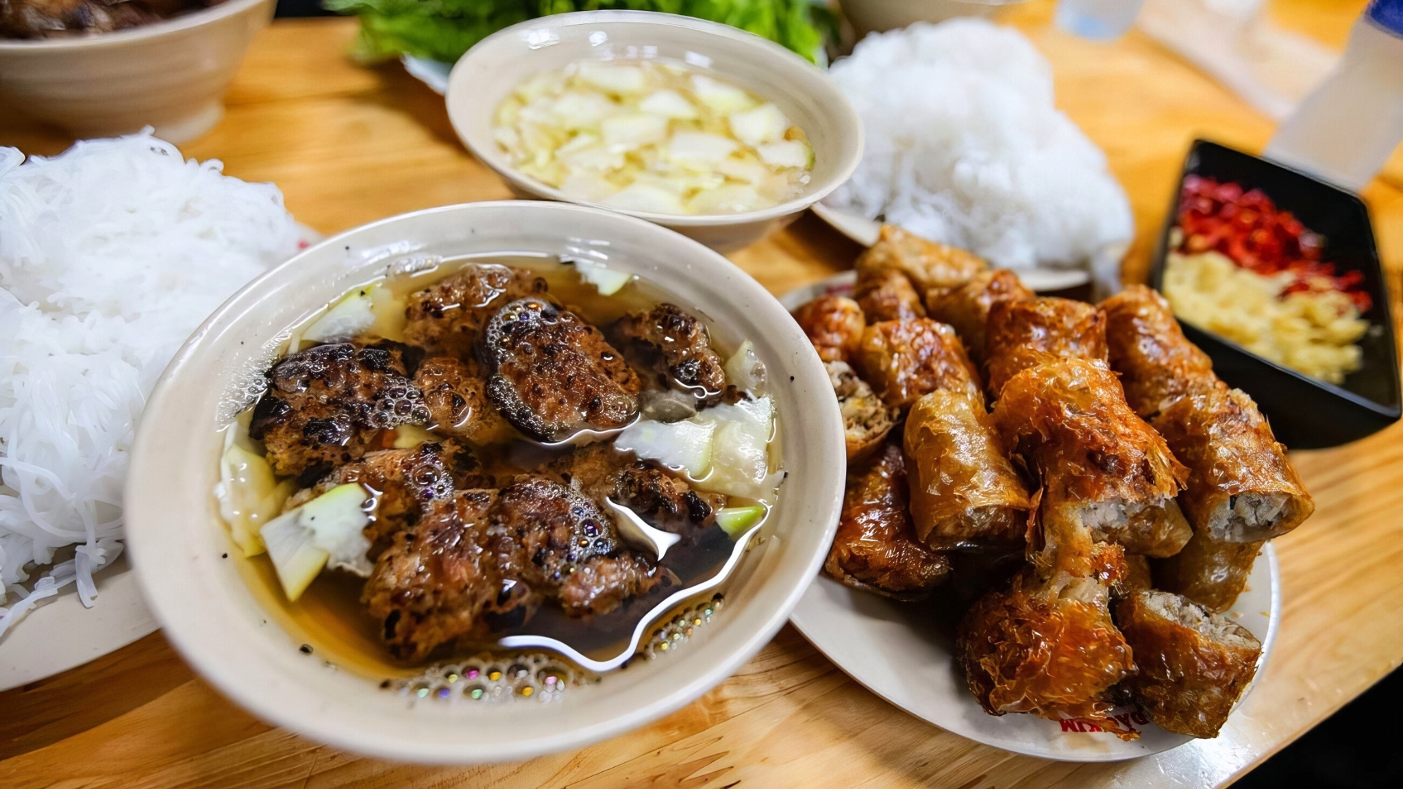 A Plate Of Bun Cha With Rice Noodles, Tender Grilled Pork, Savory Dipping Sauce, And Fresh Herbs For Added Flavor