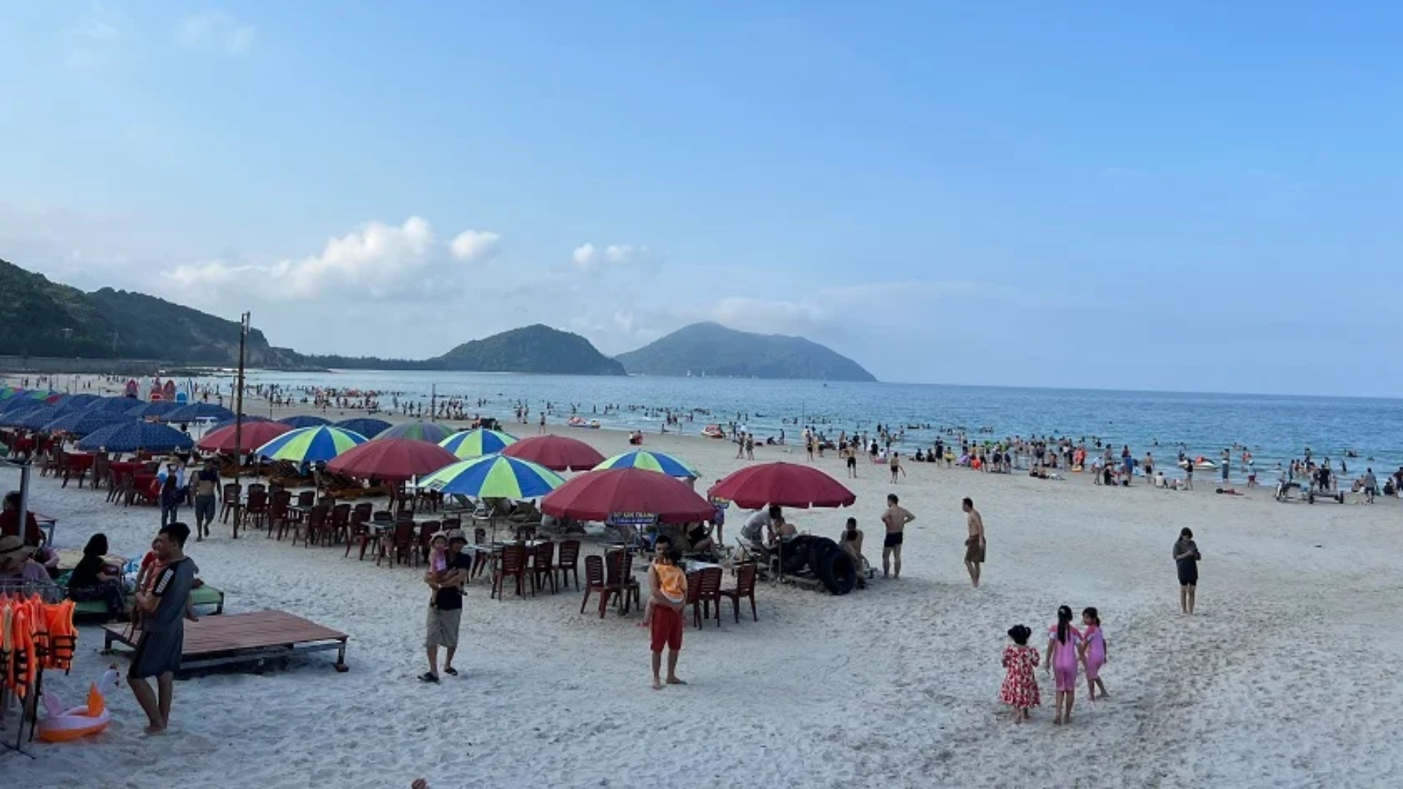Visitors relaxing and exploring the white sandy shores of Minh Chau Beach on Quan Lan Island
