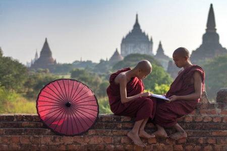 Young Monks With The Temple Strewn Skyline Of Bagan In The Background.