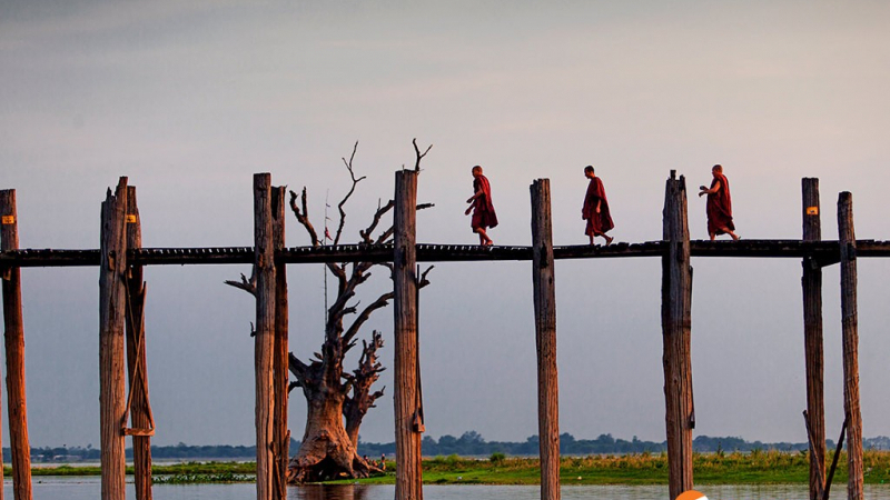 Monks Crossing The U Bein Bridge In Amarapura, The Longest Teak Wood Bridge In The World.