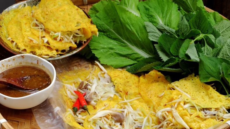 Taste Vietnamese Sizzling Crepes With Crispy Batter, Fresh Herbs, And Savory Fillings